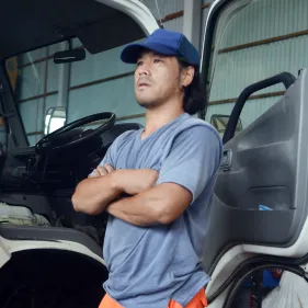 整備工場の前で腕を組み、真剣な表情を見せる男性スタッフ