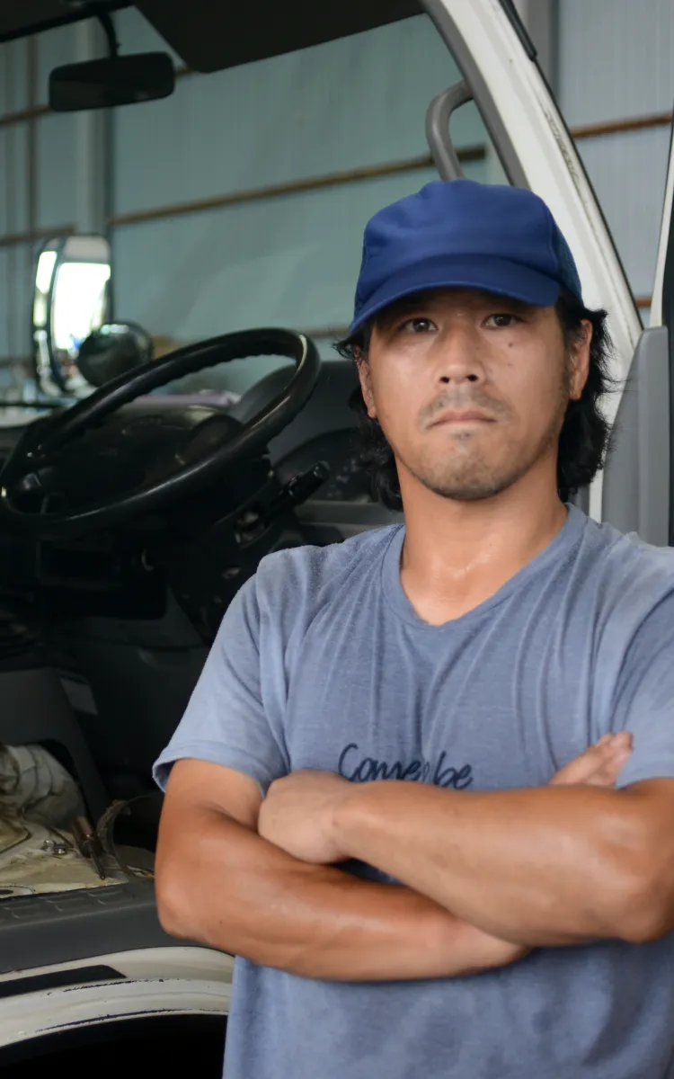 作業着を着た男性スタッフが車両整備の現場で真剣な表情を見せる様子
